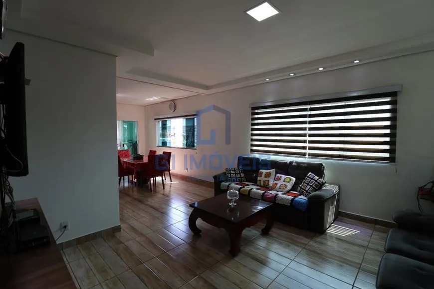 Sala de estar com sofá marrom, manta de crochê, mesa de centro e janela com persiana listrada.