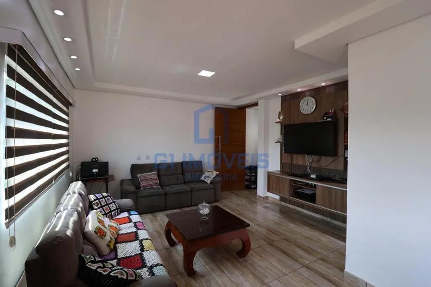 Sala de estar moderna com painel de madeira para TV, iluminação embutida no teto e piso claro.