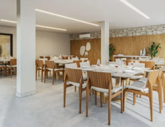 Salão de festas interno com decoração sofisticada, mesas de madeira e cadeiras de design moderno.