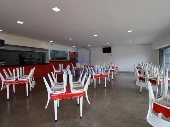 Salão interno amplo da pizzaria com piso cerâmico, mesas com cadeiras empilhadas e balcão ao fundo.