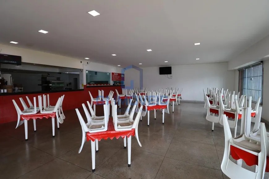 Salão interno amplo da pizzaria com piso cerâmico, mesas com cadeiras empilhadas e balcão ao fundo.