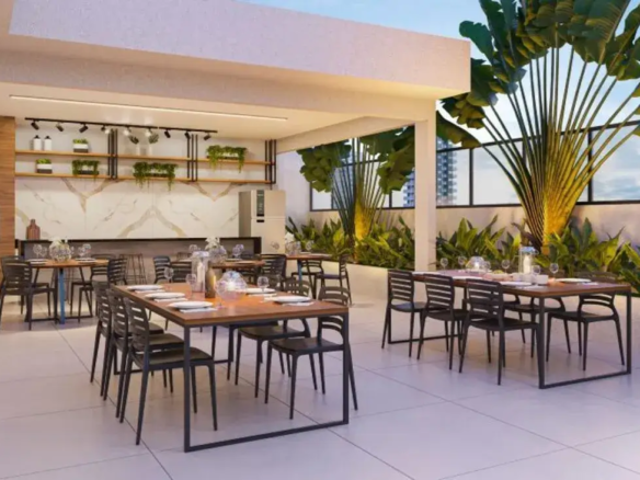 Terraço gourmet do Varandas Park equipado com churrasqueira, mesas de madeira e paisagismo tropical.