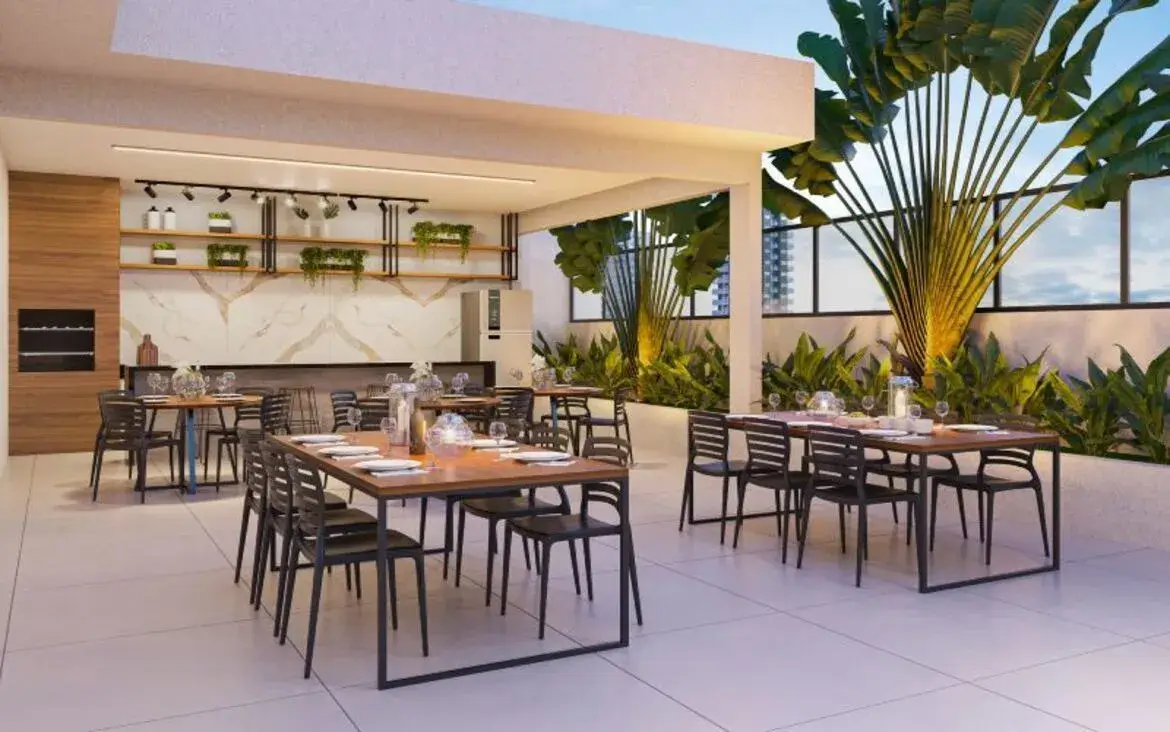 Terraço gourmet do Varandas Park equipado com churrasqueira, mesas de madeira e paisagismo tropical.