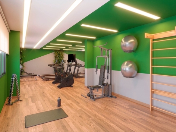 Academia do condomínio equipada com esteiras, espaldar e pesos livres.