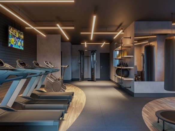 Academia do condomínio equipada com esteiras modernas, pesos livres e sacos de boxe para treino funcional.