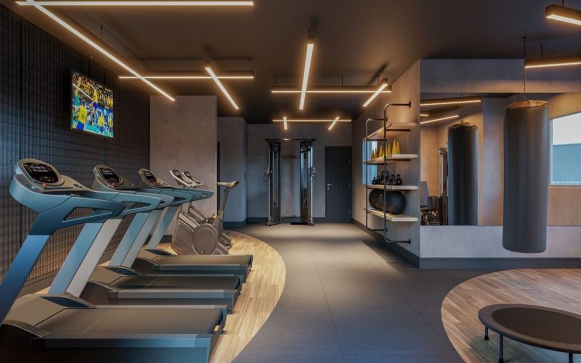 Academia do condomínio equipada com esteiras modernas, pesos livres e sacos de boxe para treino funcional.