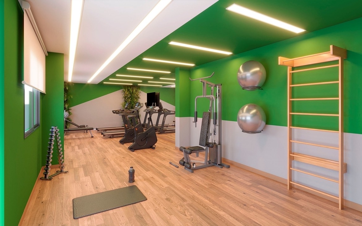 Academia do condomínio equipada com esteiras, espaldar e pesos livres.