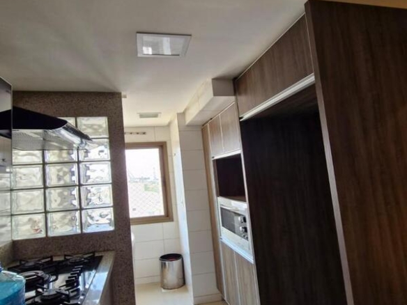 Cozinha equipada com cooktop, coifa e divisória de tijolos de vidro no Residencial Flora Viva.