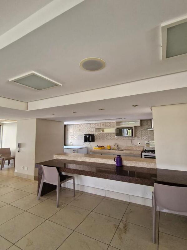 cozinha-integrada-bancada-refeicoes Área de refeições com bancada escura e cadeiras brancas de design moderno integradas à cozinha.