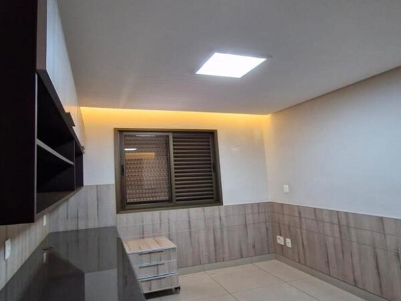 Escritório completo com ampla bancada preta e armários aéreos no Residencial Flora Viva.