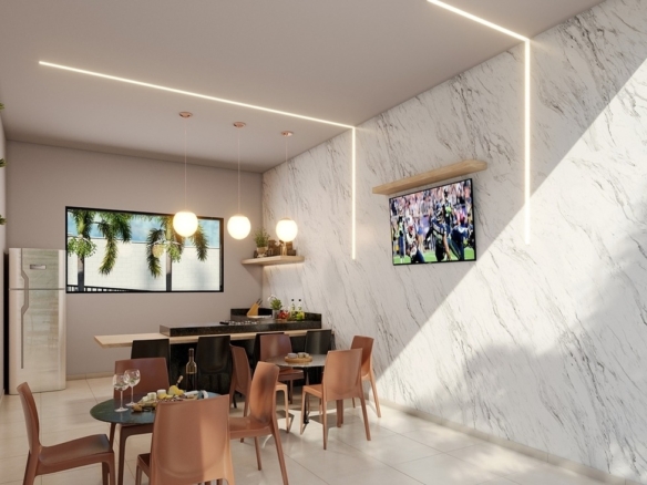 Espaço gourmet interno com acabamento em mármore, TV e mesas para jantar.