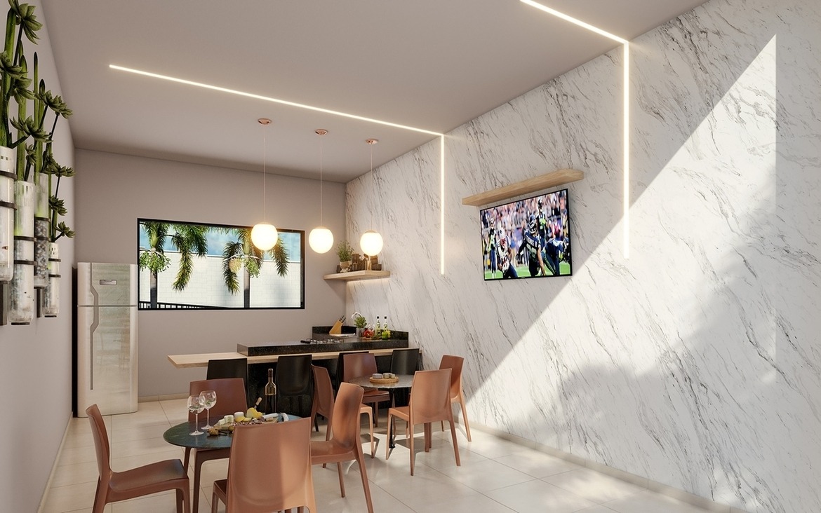 Espaço gourmet interno com acabamento em mármore, TV e mesas para jantar.