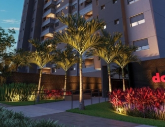 Fachada moderna do edifício Dot Bild ao anoitecer, com iluminação de destaque e paisagismo na entrada.