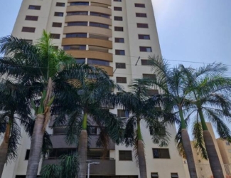 Fachada imponente do edifício Residencial Flora Viva com paisagismo e palmeiras na entrada.