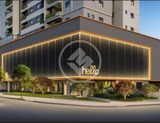 Fachada noturna iluminada do edifício Hello Viver Universitário em esquina movimentada.