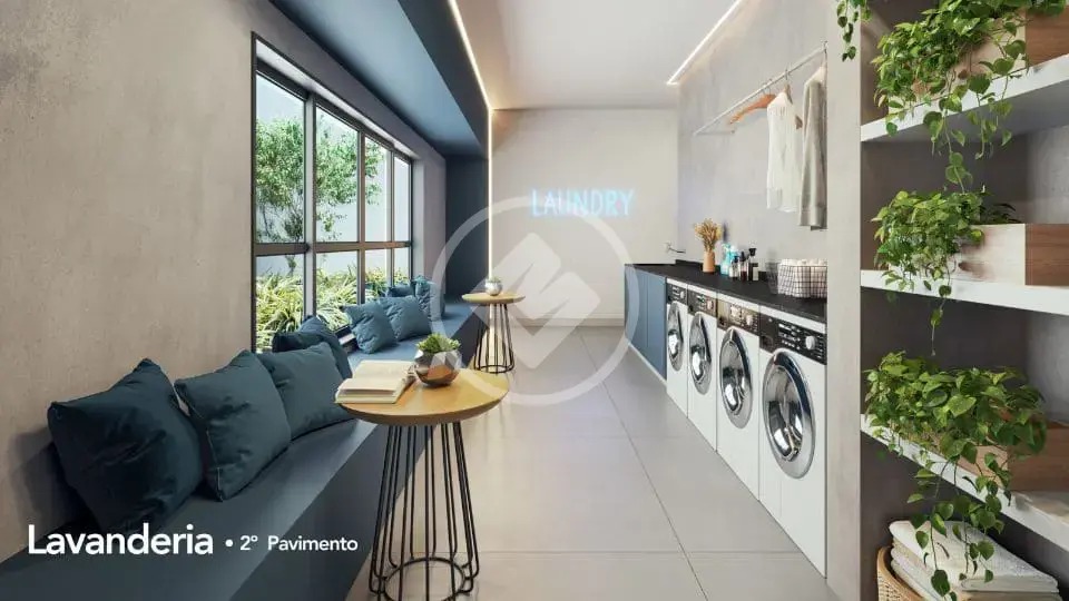 Lavanderia coletiva equipada com máquinas modernas, bancos e decoração com plantas.