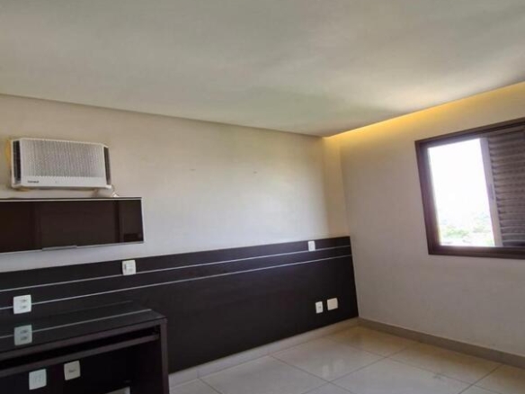 Quarto com bancada de trabalho em madeira escura, painel e ar-condicionado instalado.