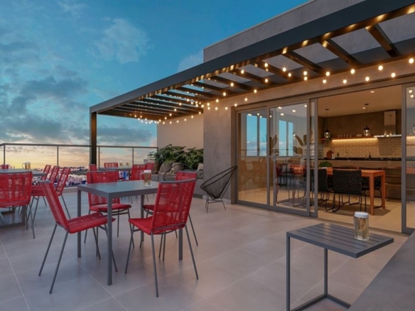 Rooftop do Dot Bild ao entardecer, com cadeiras vermelhas, varal de luzes e integração com espaço gourmet.