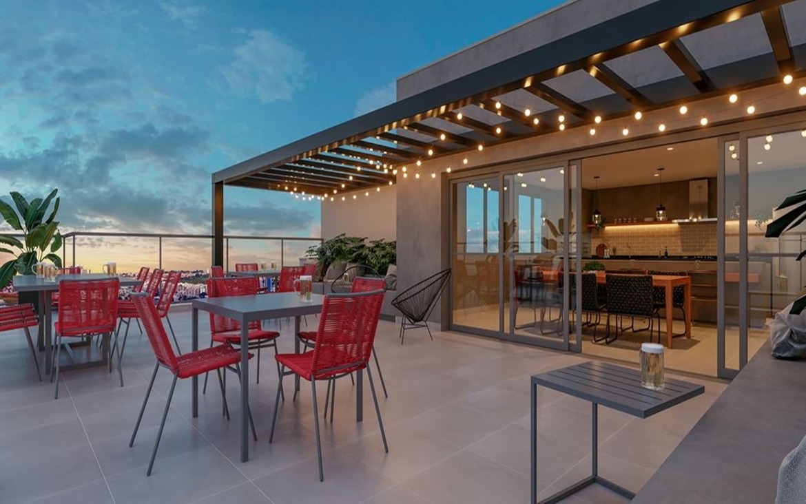 Rooftop do Dot Bild ao entardecer, com cadeiras vermelhas, varal de luzes e integração com espaço gourmet.