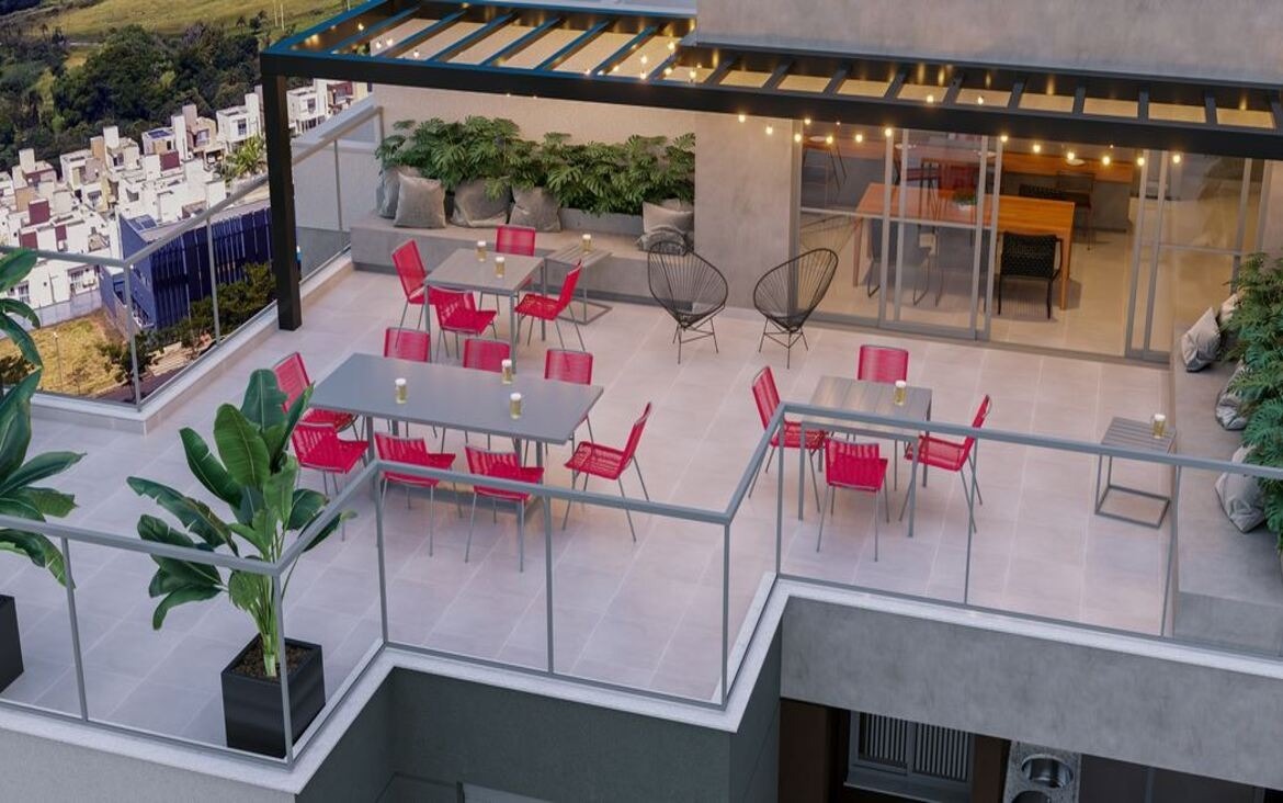 Rooftop do Dot Bild ao entardecer, com cadeiras vermelhas, varal de luzes e integração com espaço gourmet.