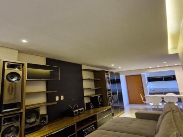 Sala de estar com sofá grande em gomos e sistema de som profissional embutido no painel.