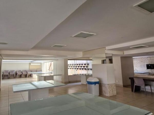 Grande salão comum com mesas de vidro e ambiente climatizado para eventos.