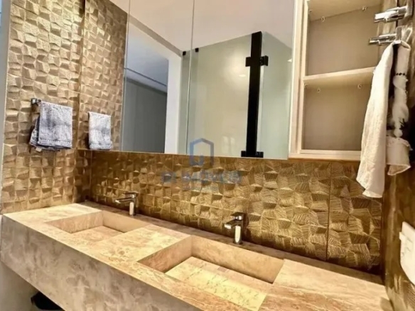 Banheiro de luxo com cuba dupla esculpida e revestimento rústico no Aldeia do Vale.