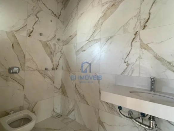 Banheiro com revestimento em porcelanato marmorizado e bancada esculpida em quartzo branco.