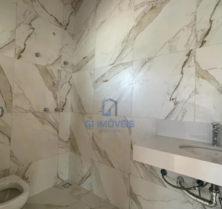Banheiro com revestimento em porcelanato marmorizado e bancada esculpida em quartzo branco.