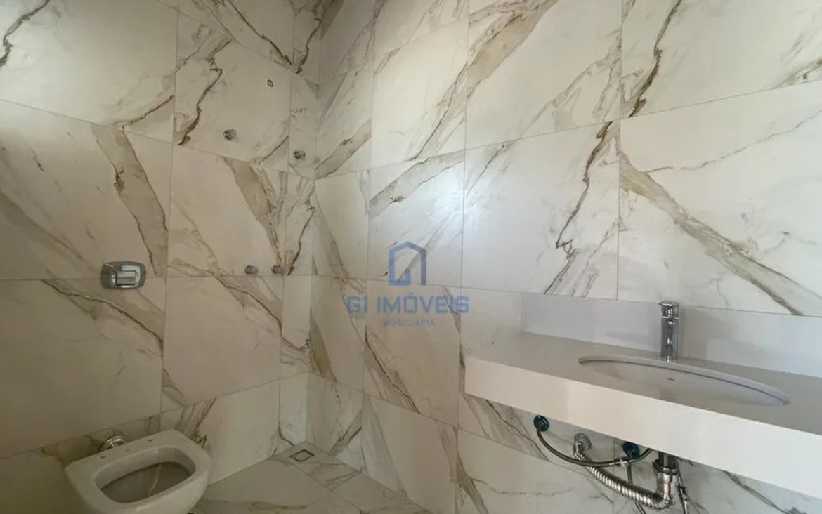 Banheiro com revestimento em porcelanato marmorizado e bancada esculpida em quartzo branco.