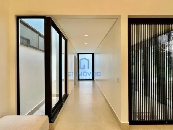 Corredor interno minimalista com painel ripado e portas de vidro no Aldeia do Vale.