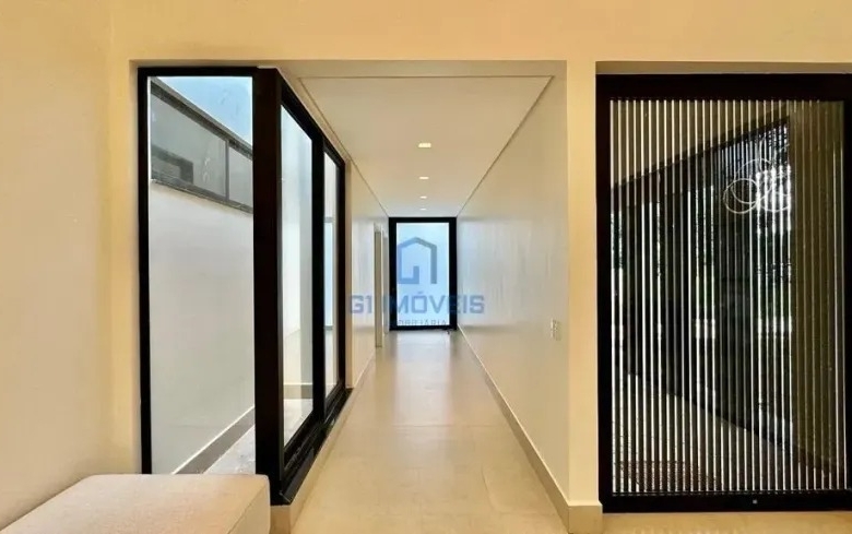 Corredor interno minimalista com painel ripado e portas de vidro no Aldeia do Vale.