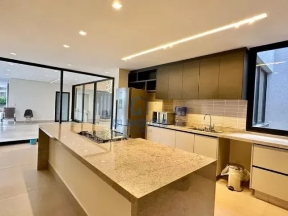 Cozinha gourmet planejada com ilha central em pedra e armários amadeirados.