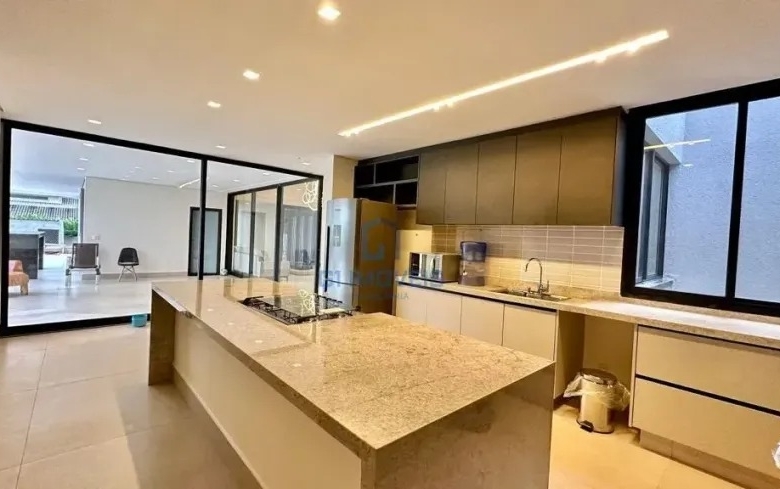 Cozinha gourmet planejada com ilha central em pedra e armários amadeirados.