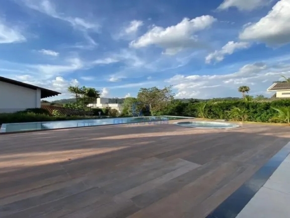 Deck de madeira externo com vista para área verde ao entardecer.