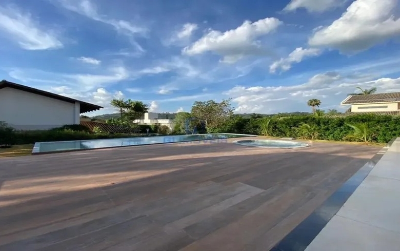 Deck de madeira externo com vista para área verde ao entardecer.