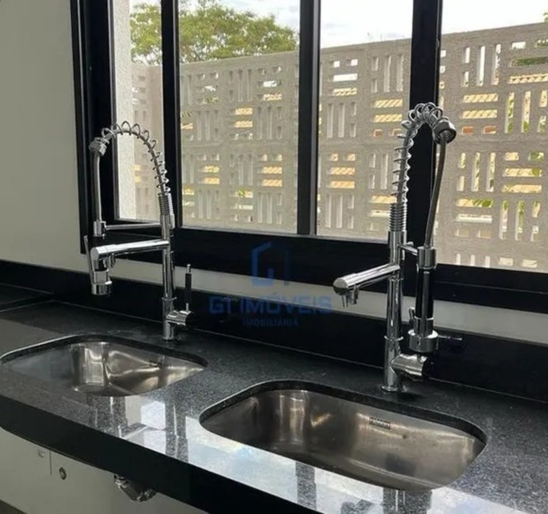 Detalhe de acabamento premium com torneira monocomando gourmet e cuba dupla em aço inox.