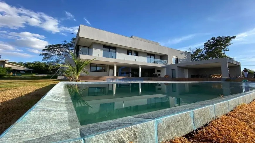 fachada-casa-moderna-piscina Fachada de casa moderna de luxo com piscina e deck de pedra sob céu azul.