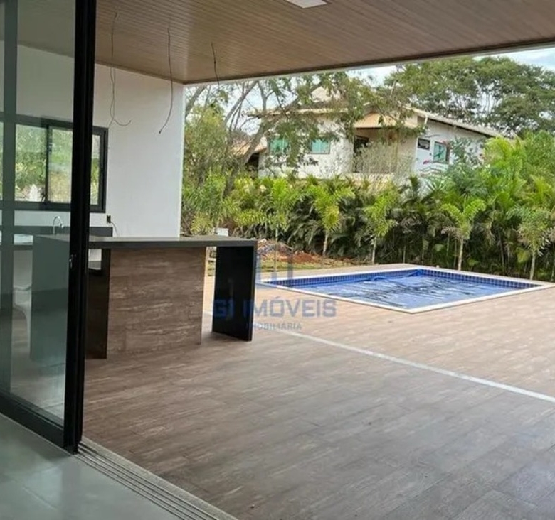 Vista interna da sala integrada com o deck da piscina no Residencial Aldeia do Vale através de esquadrias de alto padrão.