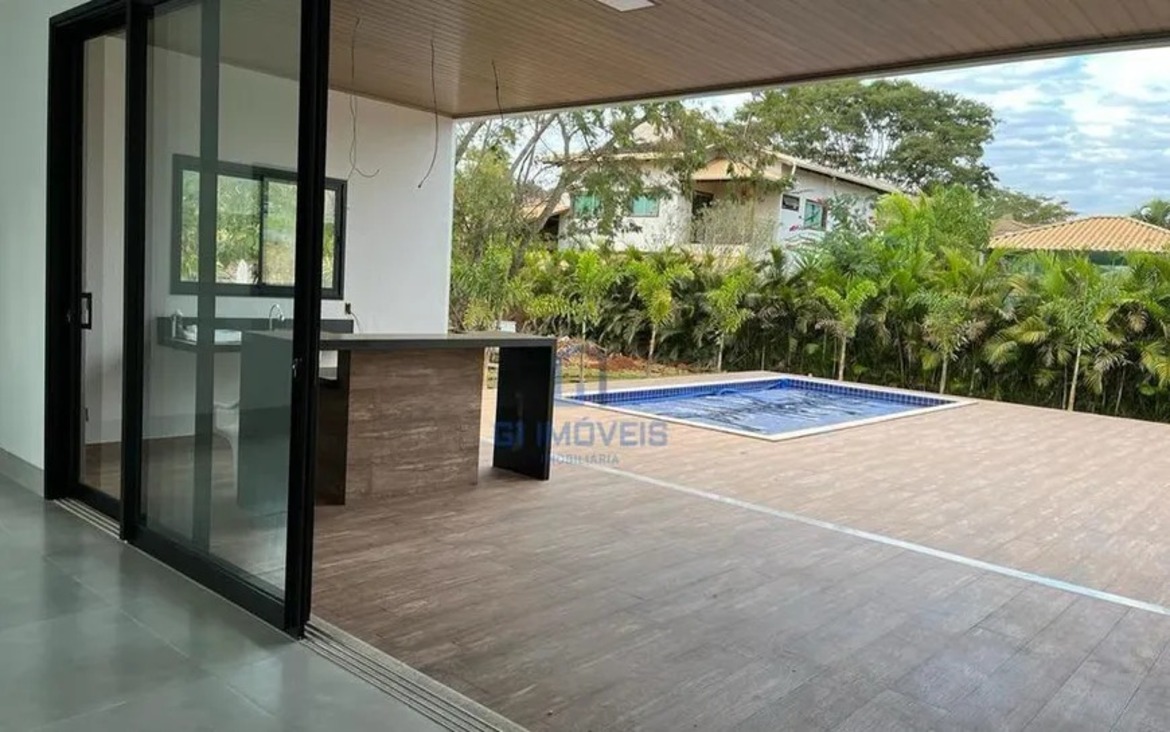 Vista interna da sala integrada com o deck da piscina no Residencial Aldeia do Vale através de esquadrias de alto padrão.