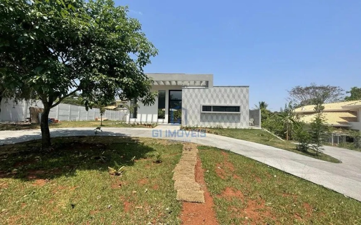 Entrada da residência no Residencial Aldeia do Vale destacando o paisagismo com árvores preservadas e calçada em pedra.