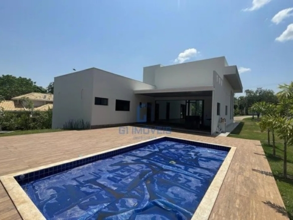 Piscina privativa revestida em pastilhas azuis com amplo deck de madeira e projeto paisagístico ao fundo.