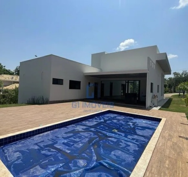 Piscina privativa revestida em pastilhas azuis com amplo deck de madeira e projeto paisagístico ao fundo.