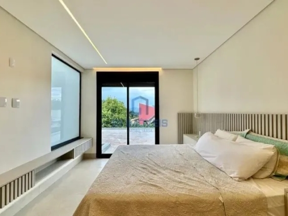 Quarto iluminado com mesa de estudos lateral e vista para o jardim.