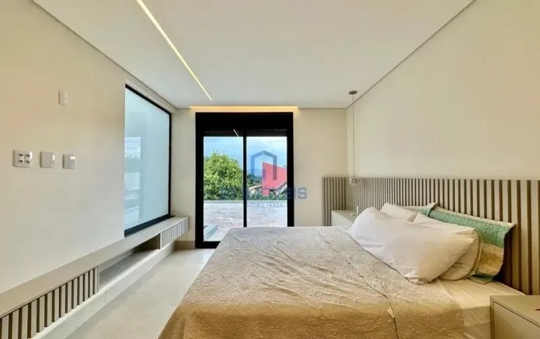 Quarto iluminado com mesa de estudos lateral e vista para o jardim.