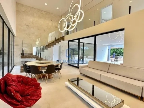 Sala de estar com pé-direito duplo, sofás brancos e grandes aberturas de vidro.