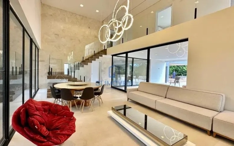 Sala de estar com pé-direito duplo, sofás brancos e grandes aberturas de vidro.