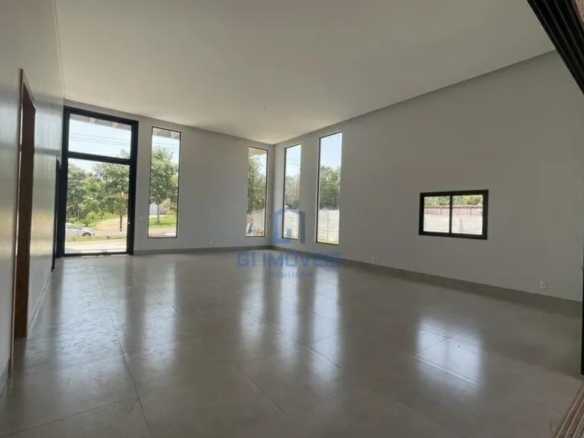 Sala de estar com pé-direito elevado e grandes aberturas de vidro para máxima iluminação natural.