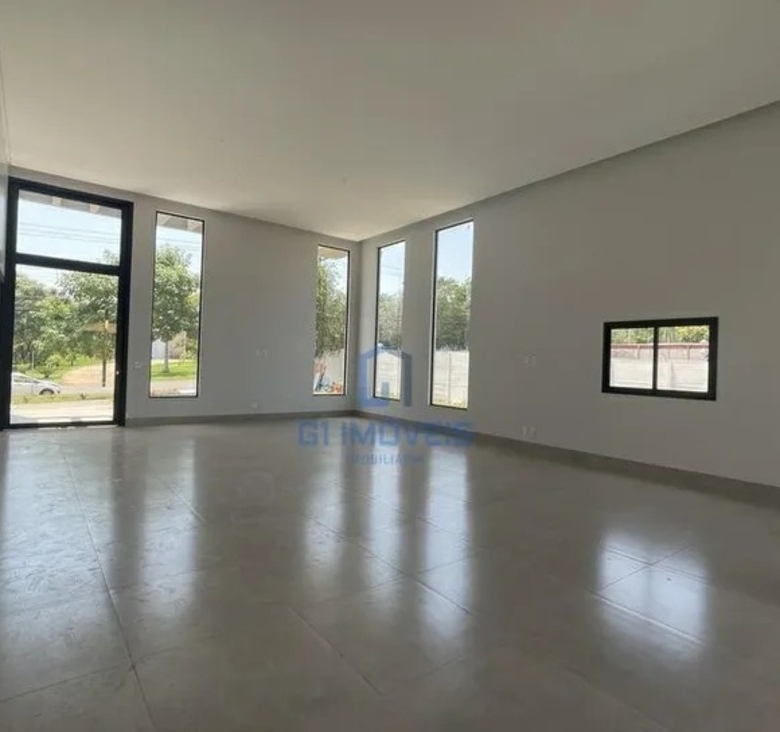 Sala de estar com pé-direito elevado e grandes aberturas de vidro para máxima iluminação natural.