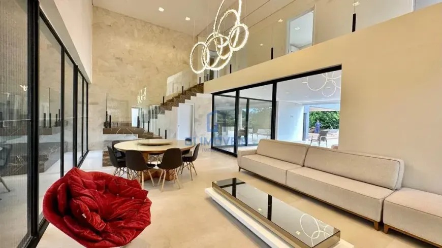 sala-estar-pe-direito-duplo Sala de estar com pé-direito duplo, sofás brancos e grandes aberturas de vidro.